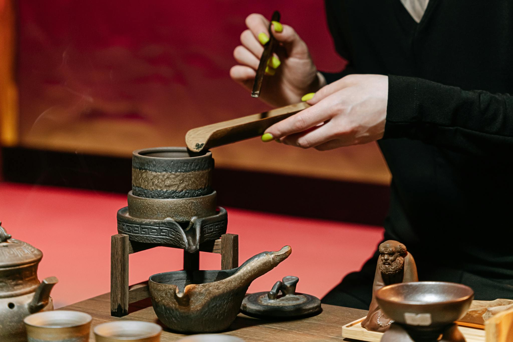 Services服務 Close-up of hands conducting a traditional tea ceremony with pottery teapot and utensils.